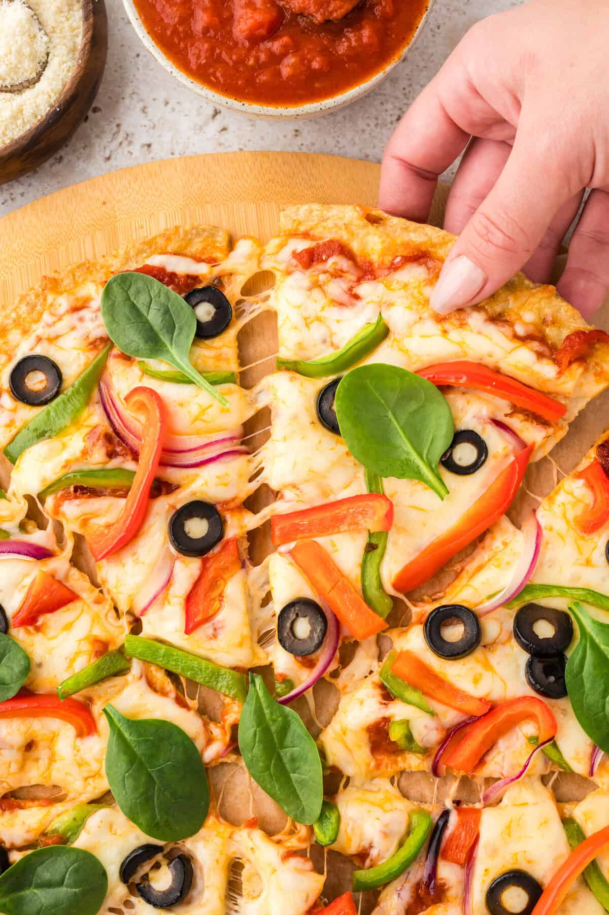 Hand grabbing a slice of keto chicken crust pizza.