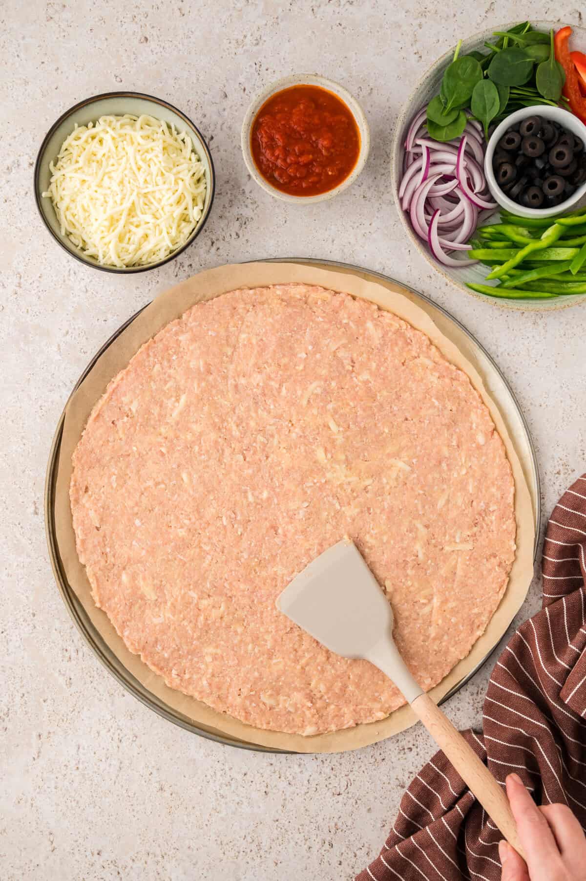 Ground chicken mixture spread into pizza pan.