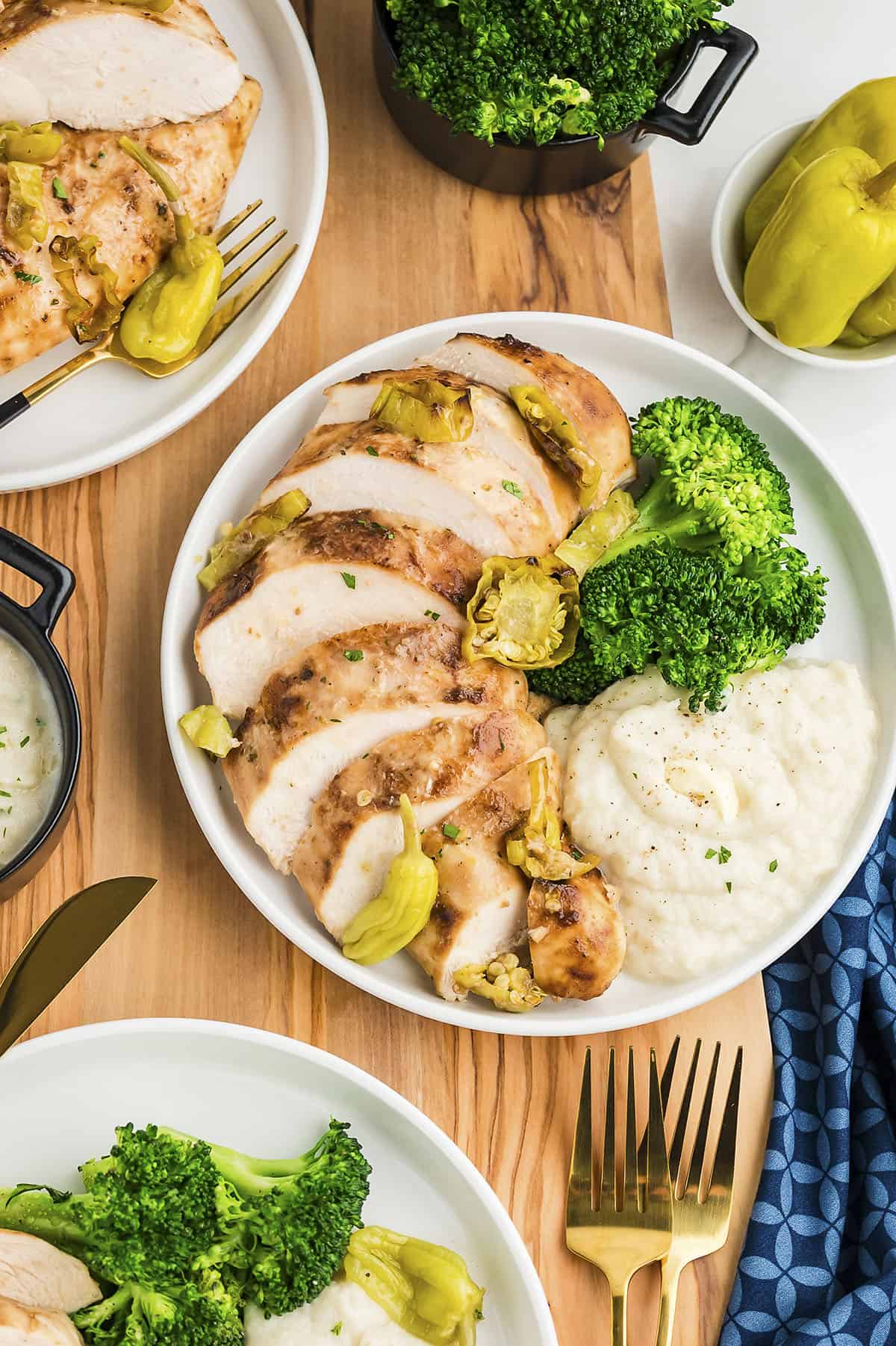 Sliced Mississippi chicken on white plate with mashed cauliflower and steamed broccoli.