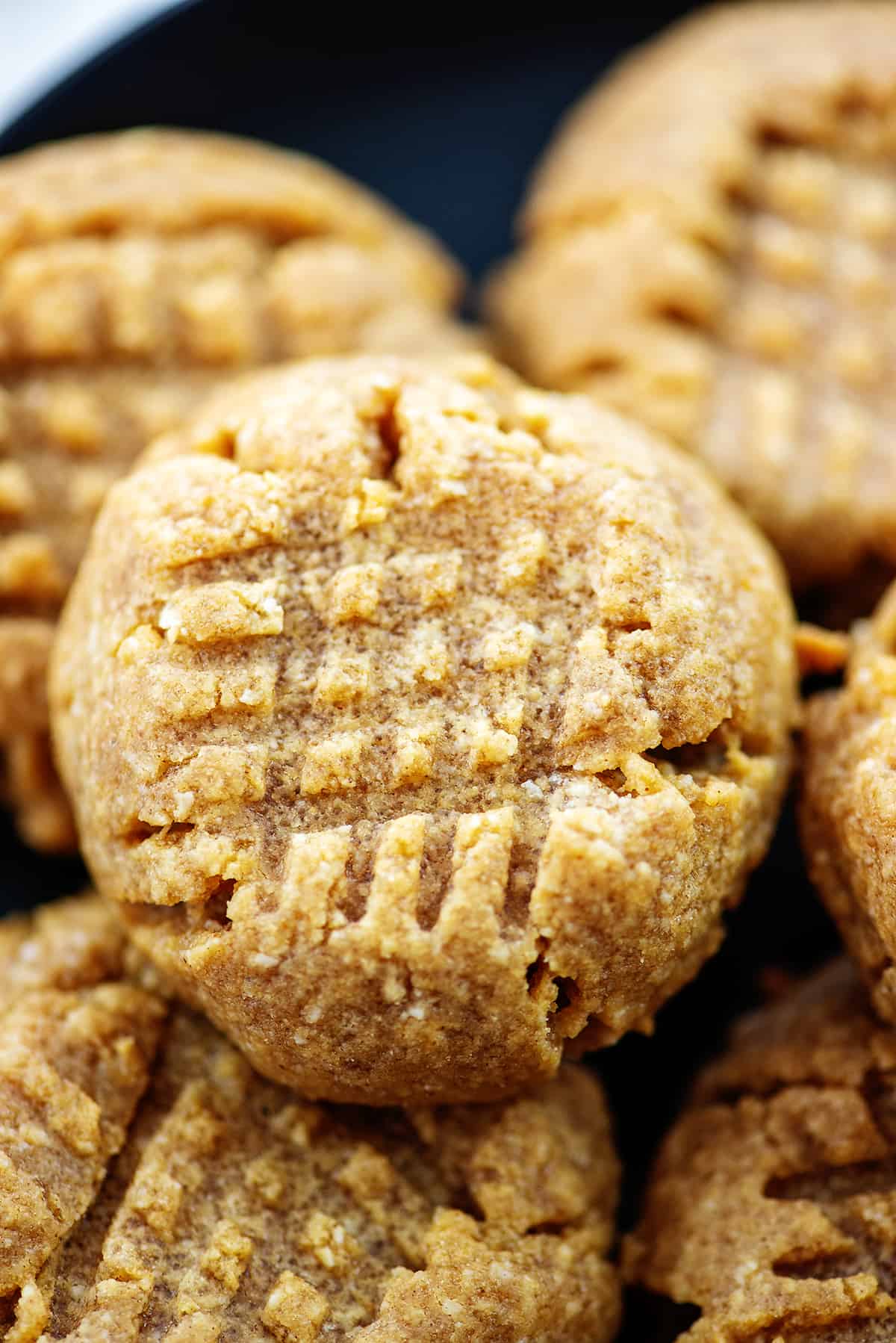 pile of almond flour peanut butter cookies on black plate.