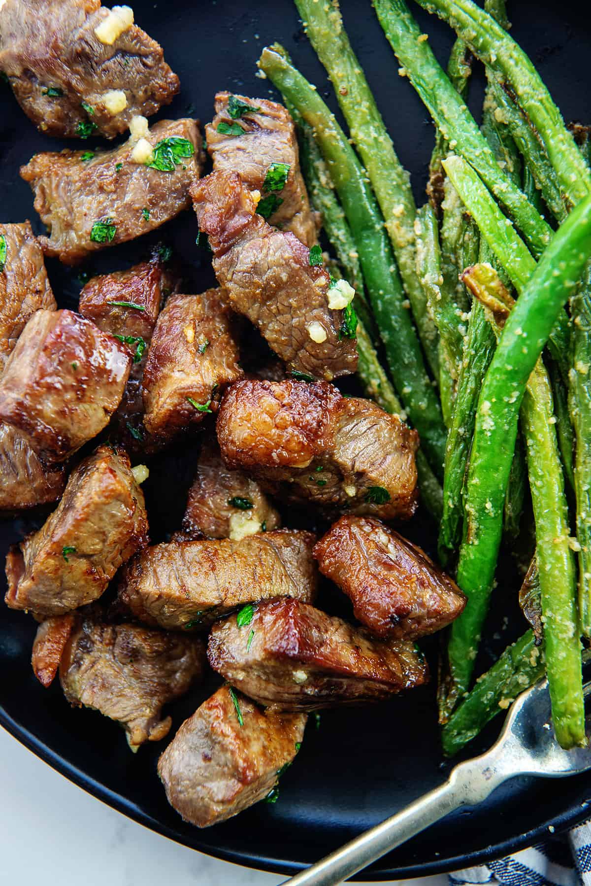 tender steak bites on black plate.