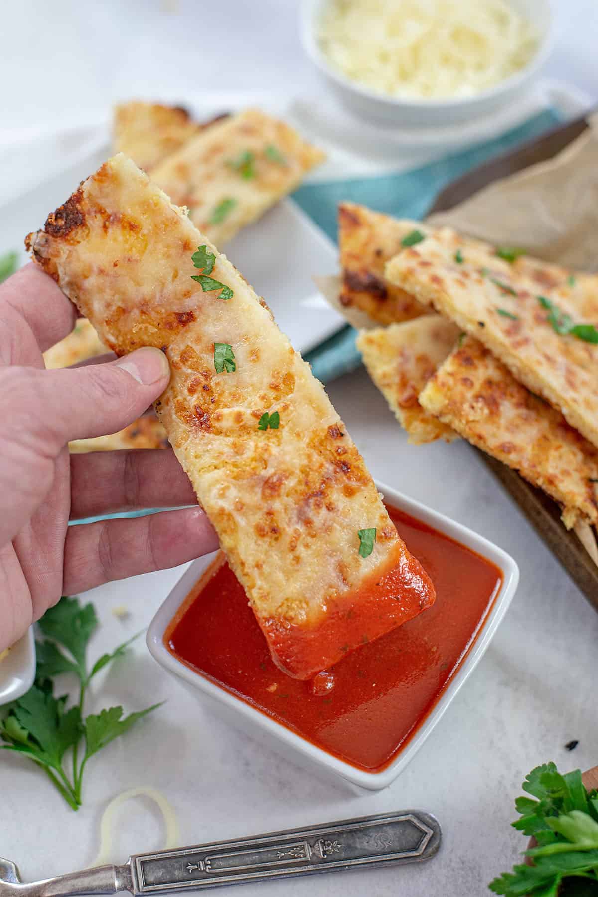 keto cauliflower breadstick being dipped in marinara.