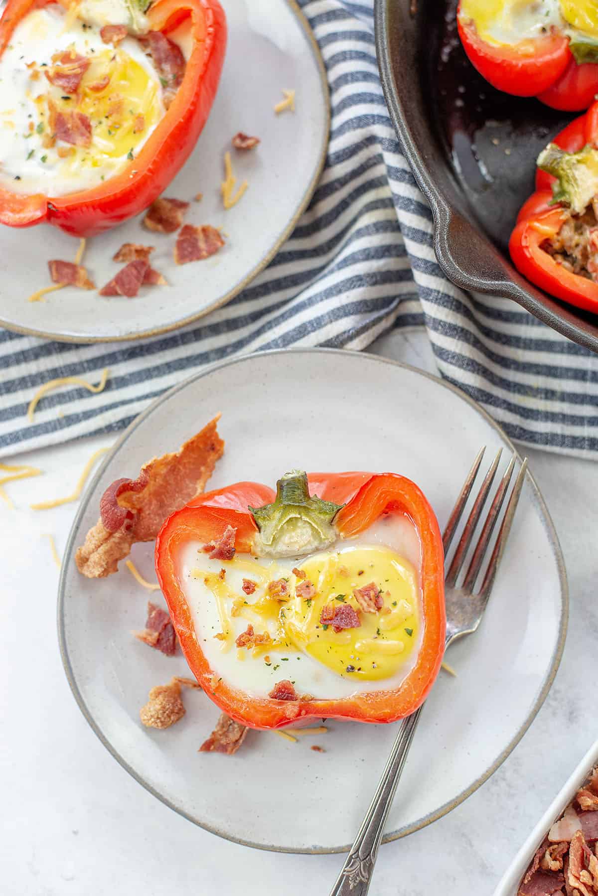 bacon and egg stuffed peppers on small plates.
