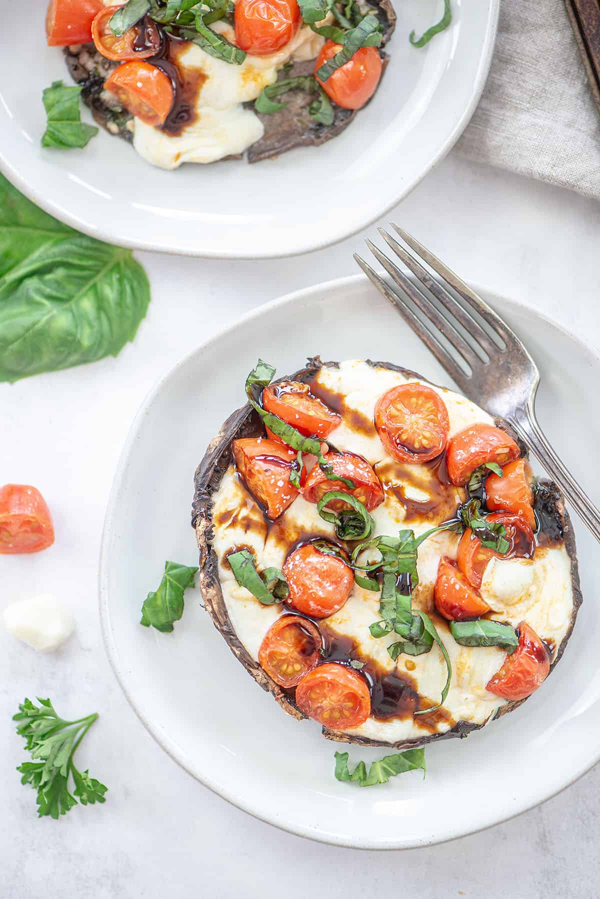 Caprese stuffed mushrooms on small white plates.