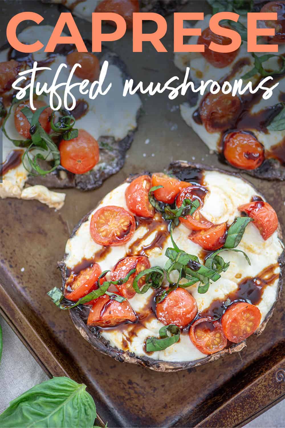 mushroom caps stuffed with tomato and mozzarella on sheet pan.