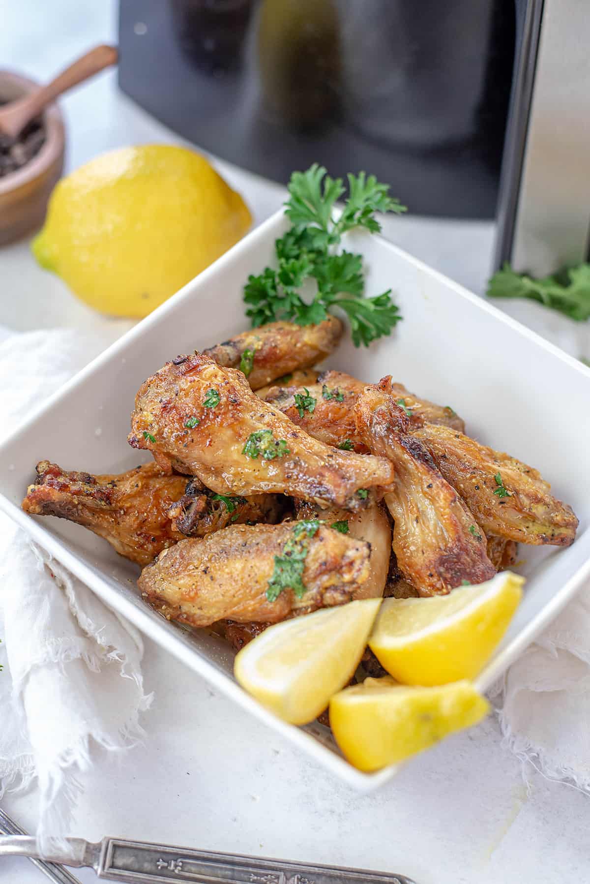 air fryer lemon pepper wings in white bowl.