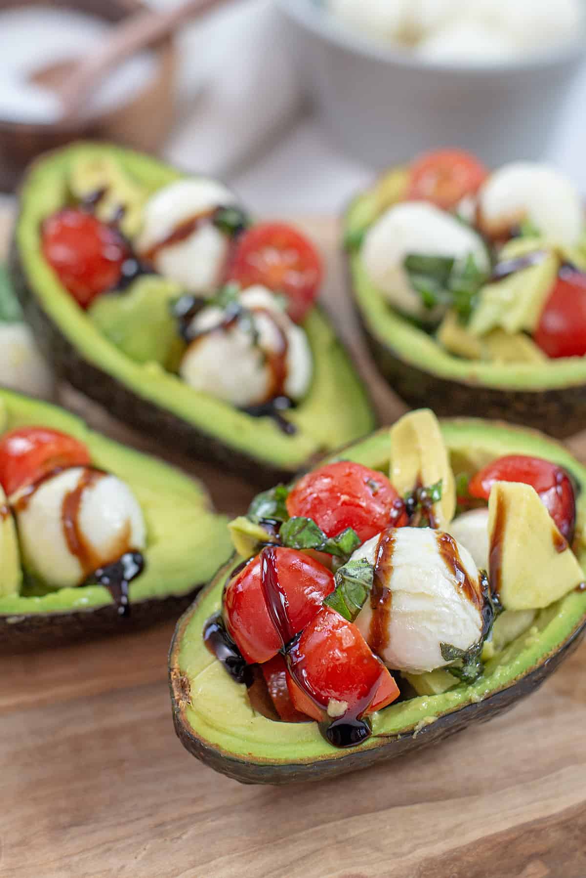 caprese stuffed avocados on wooden board.