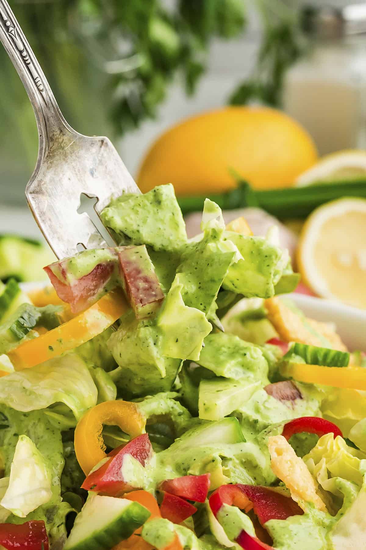 Salad topped with green goddess dressing on a fork.