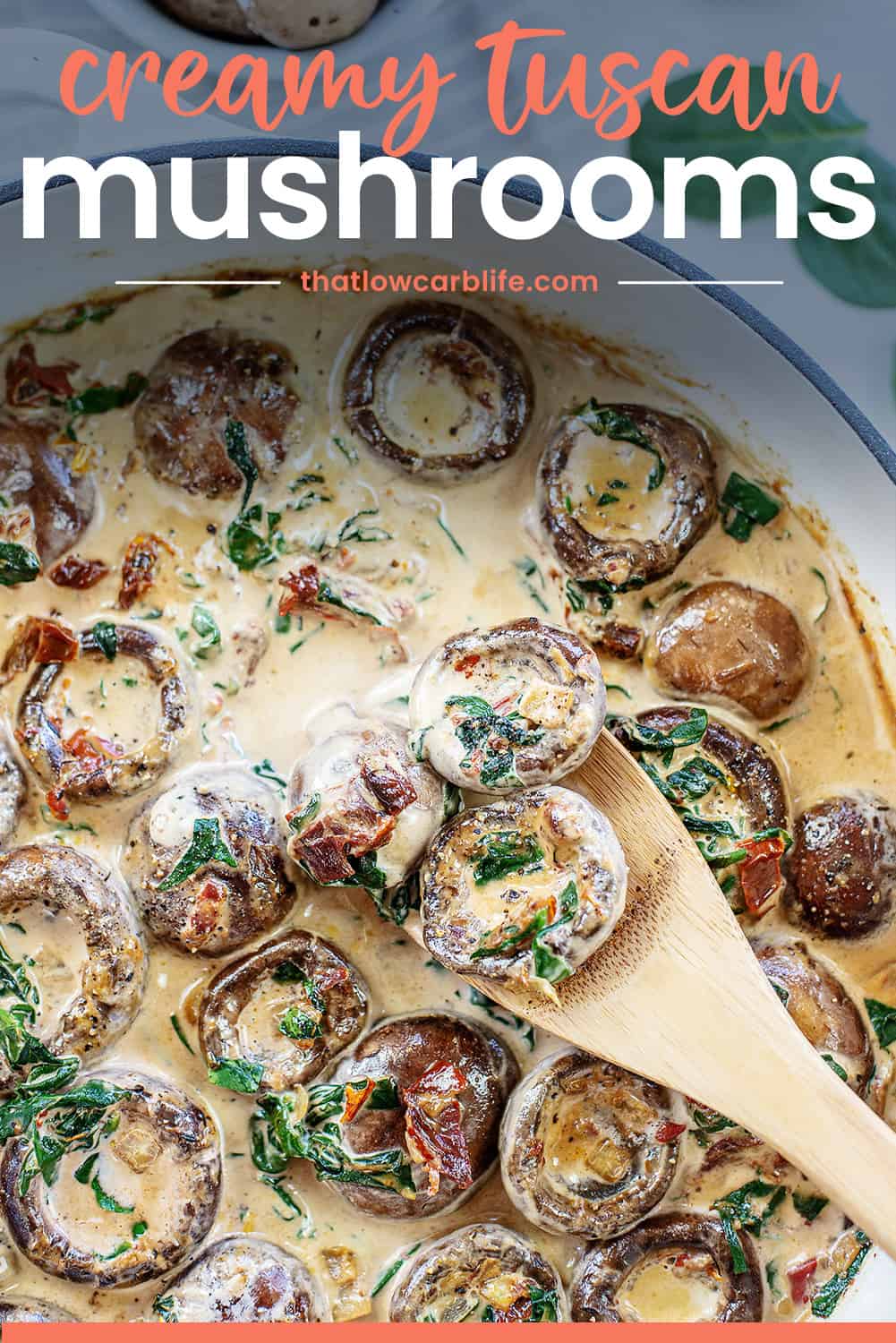 creamy tuscan mushrooms in pan with wooden spoon.