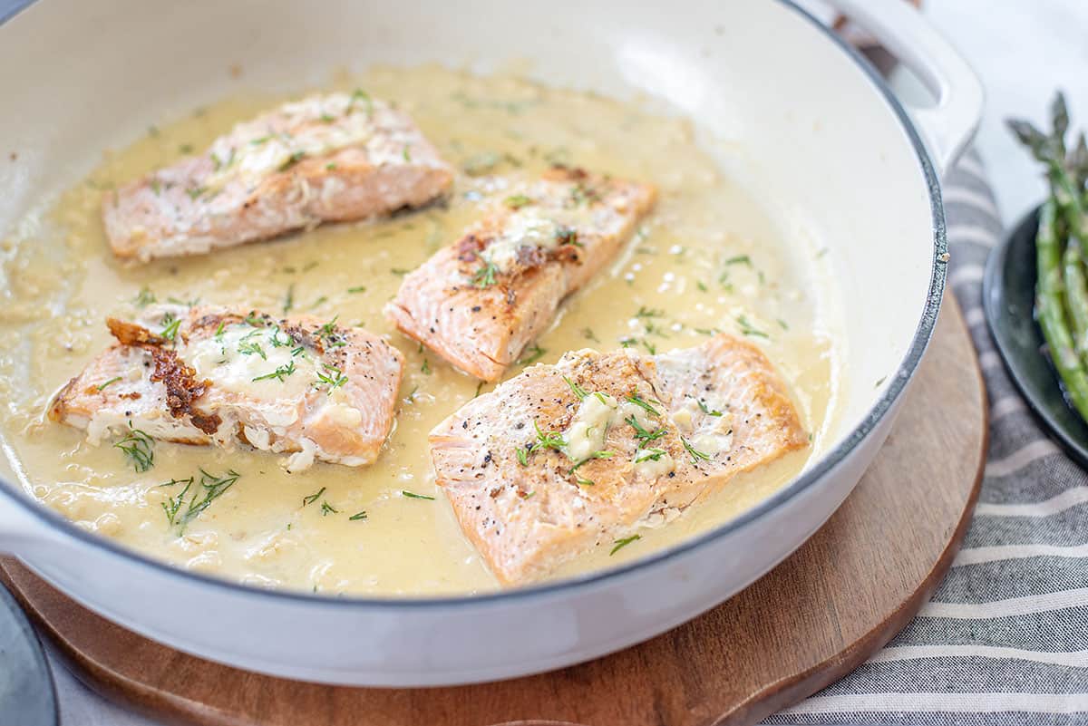 salmon in skillet with lemon dill sauce.