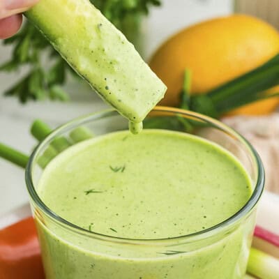 Cucumber being dipped in green goddess dressing.