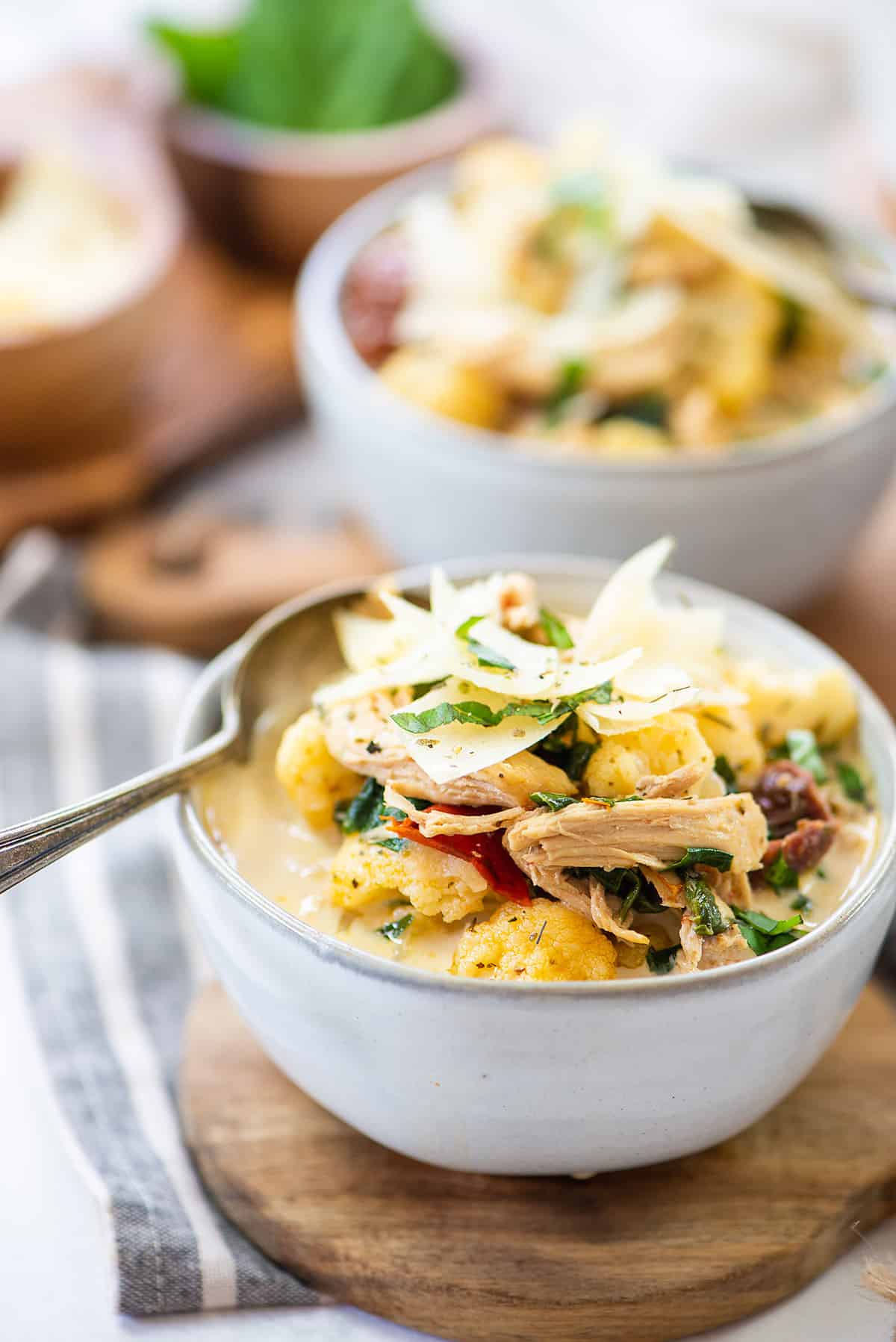 bowl of Tuscan chicken soup on small round board.