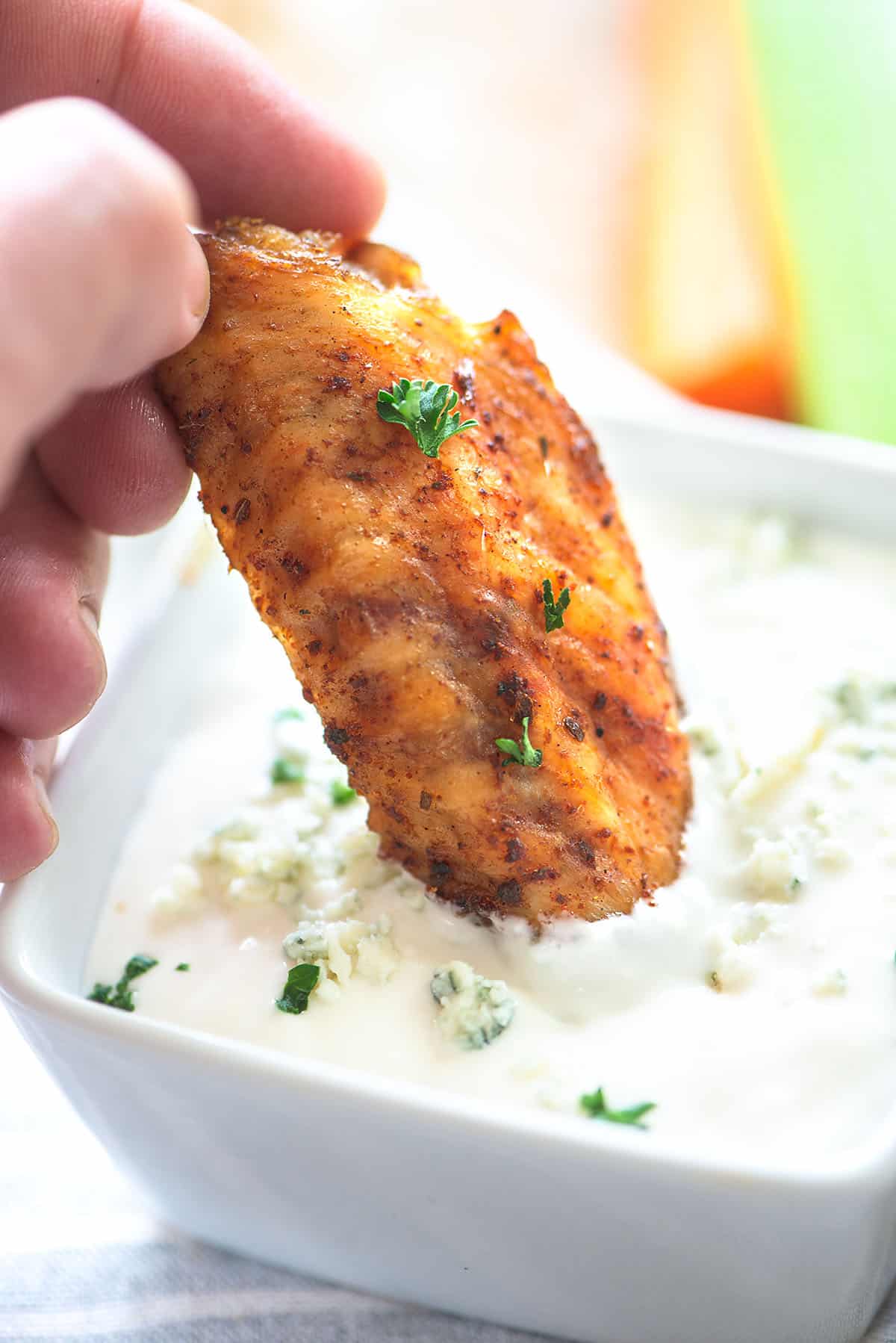 dry rub chicken wing being dipped in blue cheese dip.