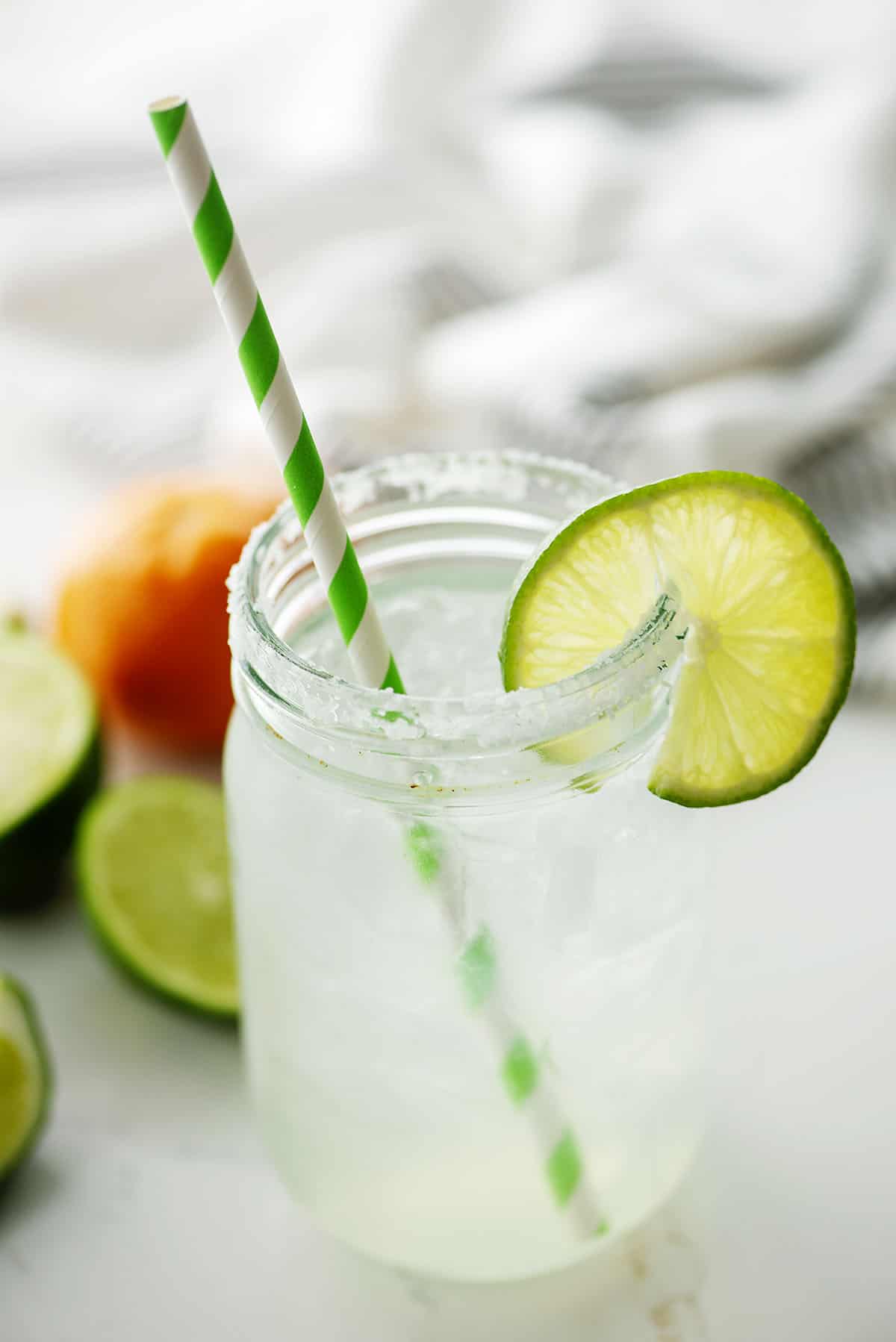margarita in glass with green striped straw.