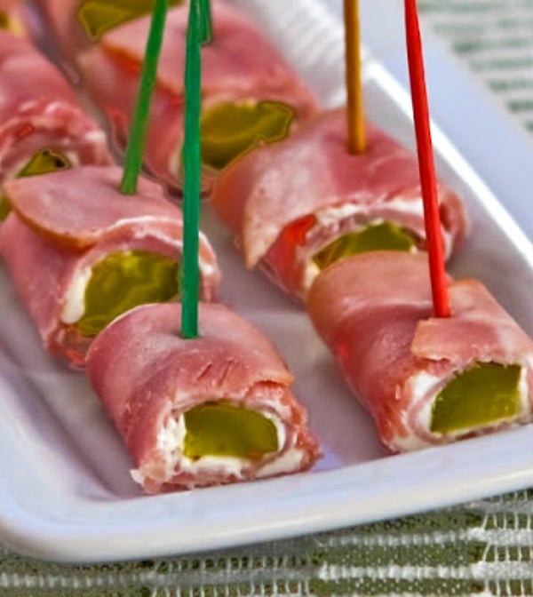 Keto ham dill pickle bites on a white plate held together with toothpicks.