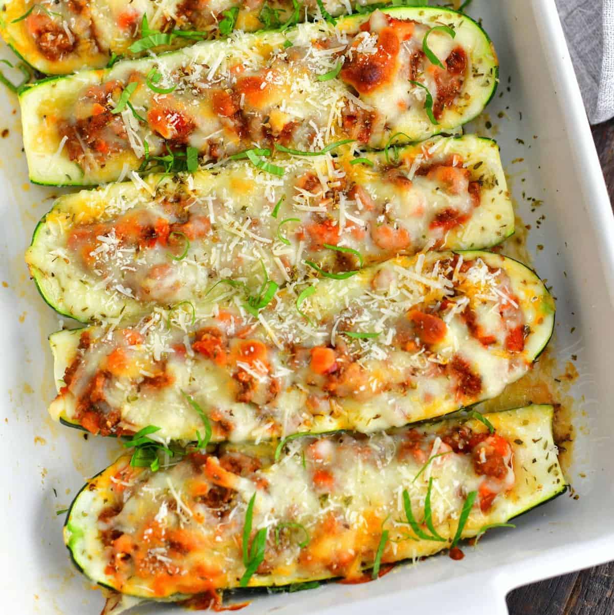 A top down view of a white baking dish with beef zucchini boats.