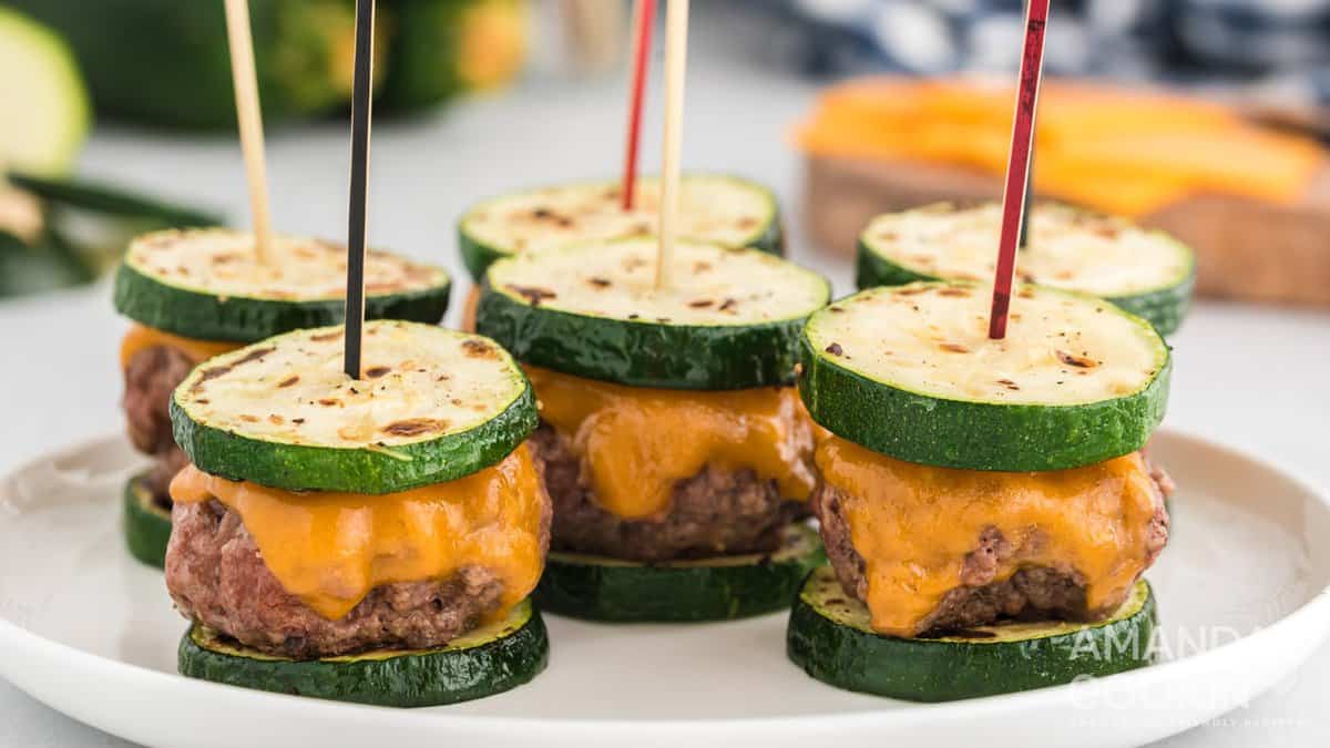 A white plate with six zucchini sliders held together with toothpicks.
