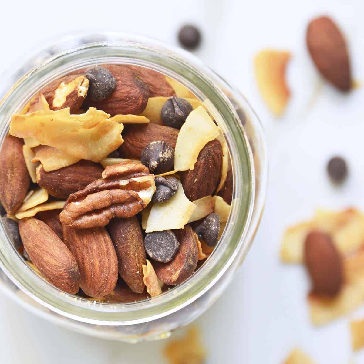 A top down view of a glass jar containing almond joy keto trail mix.