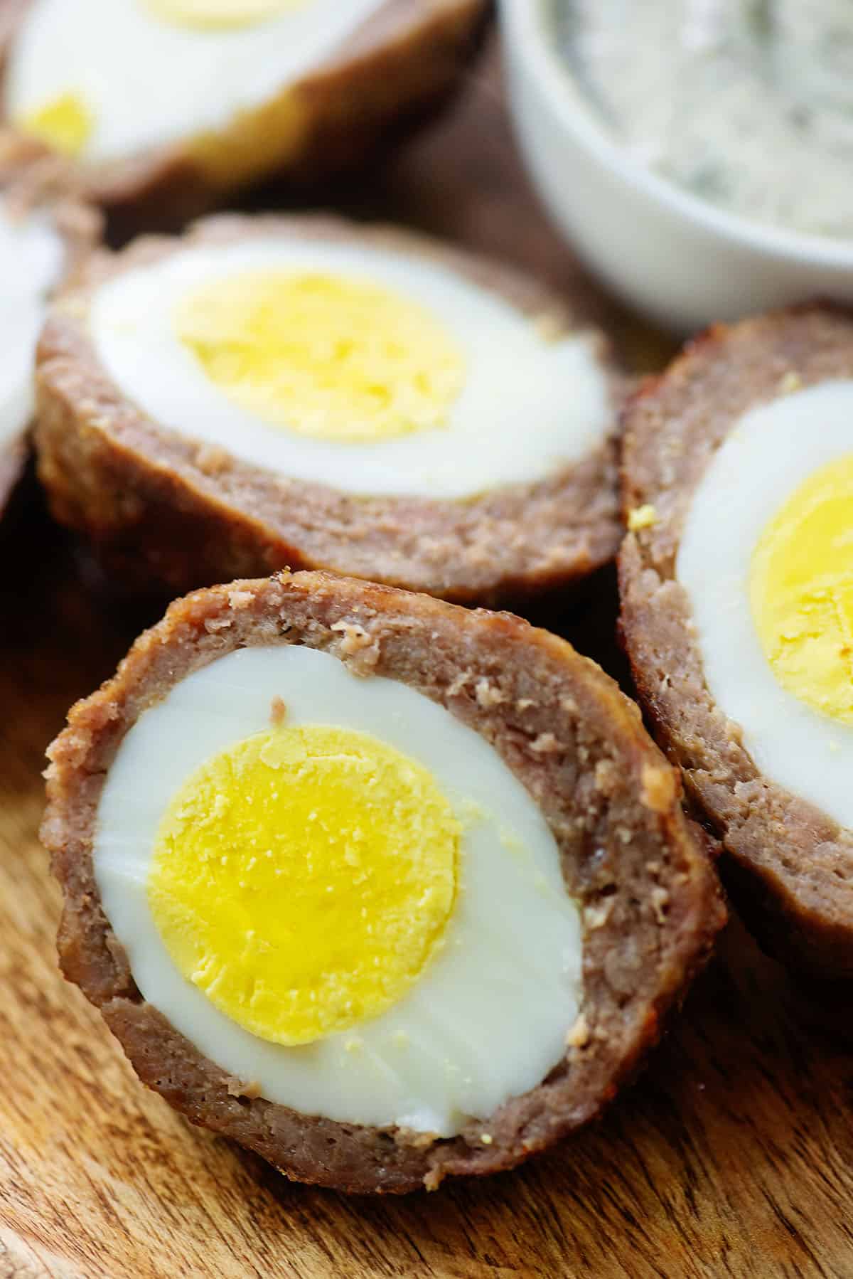 A close up view of keto scotch eggs sliced in half on a cutting board.