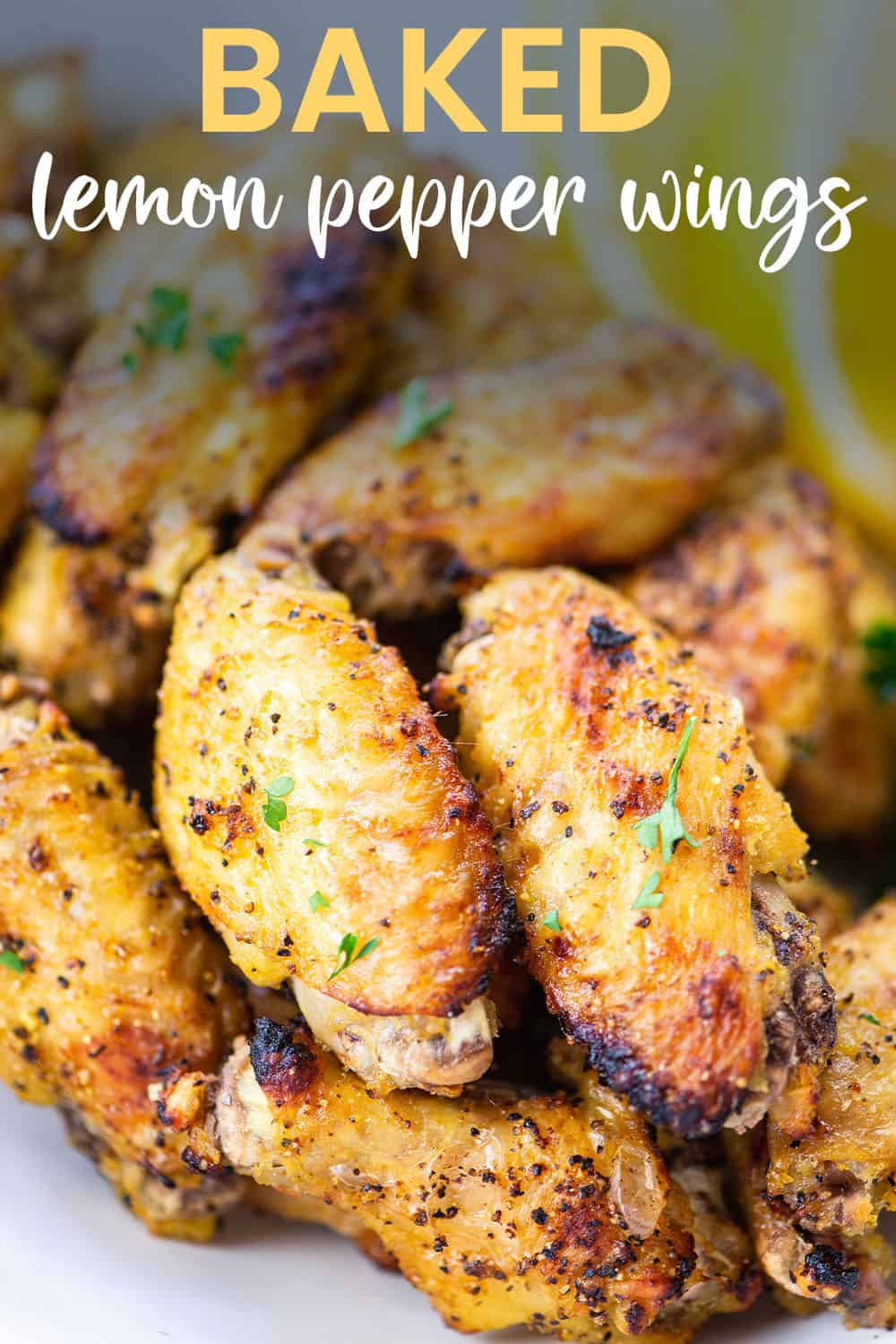 baked lemon pepper chicken wings in white bowl with text for Pinterest.