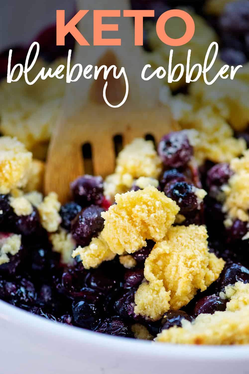 keto blueberry cobbler in baking dish with wooden spoon.