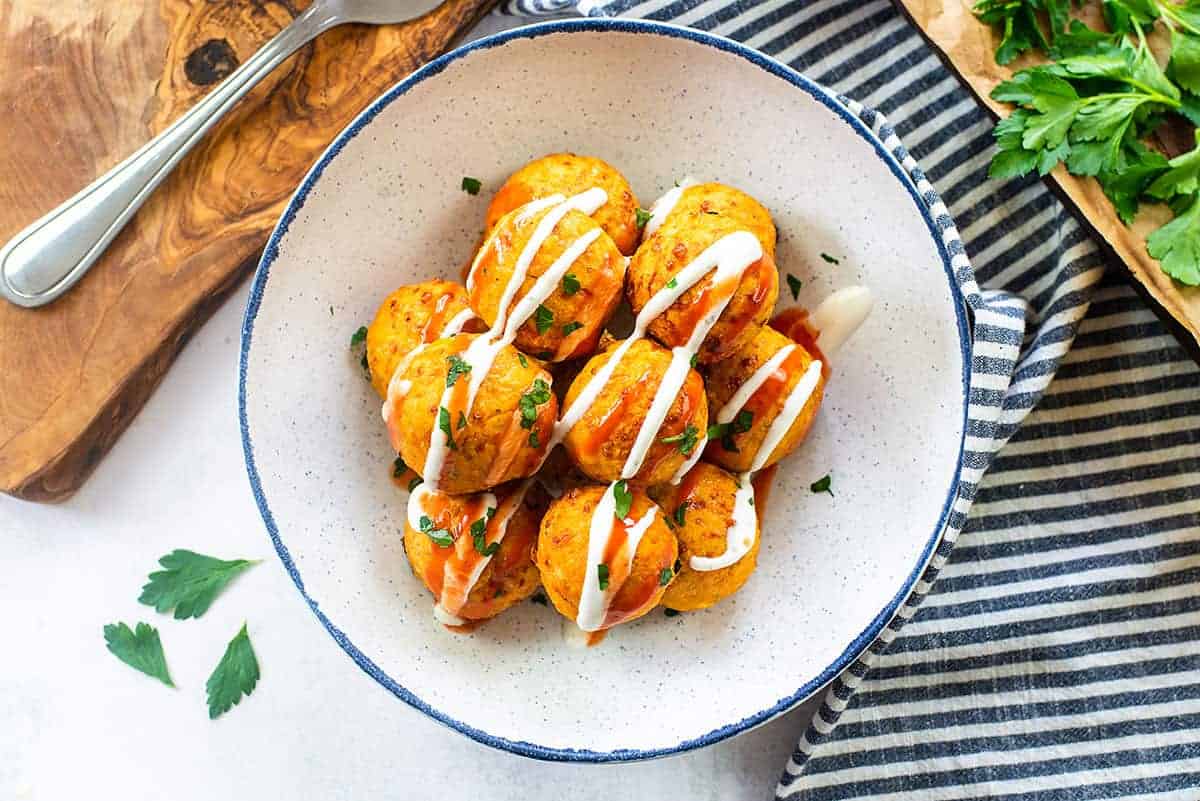 A top down view of low carb buffalo chicken meatballs on a blue and white bowl.