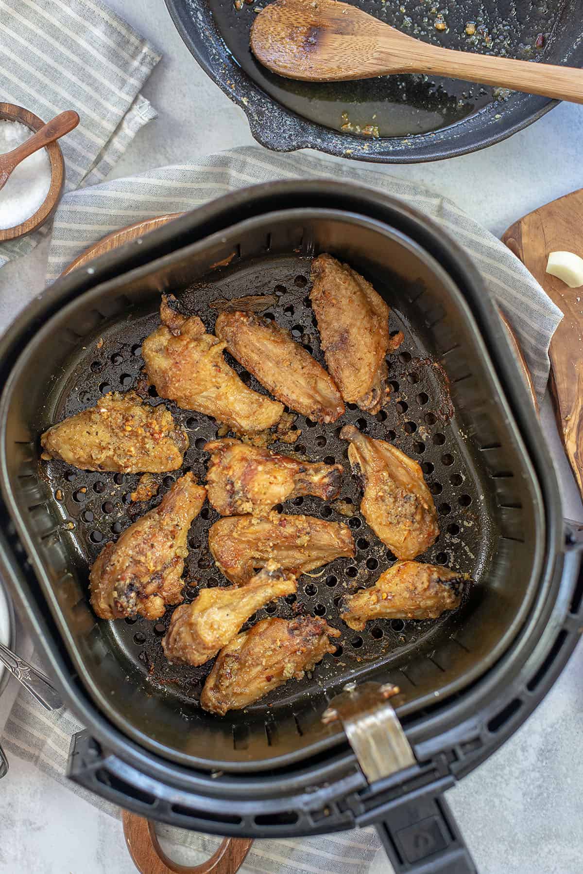 A top down view of an air fryer basket containing garlic parmesan chicken wings.