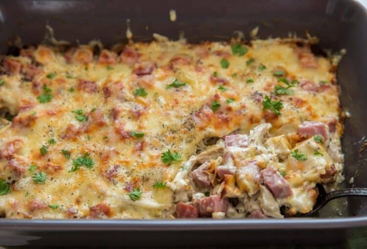 A baking dish with chicken cordon bleu casserole and a fork scooping some of the casserole out.
