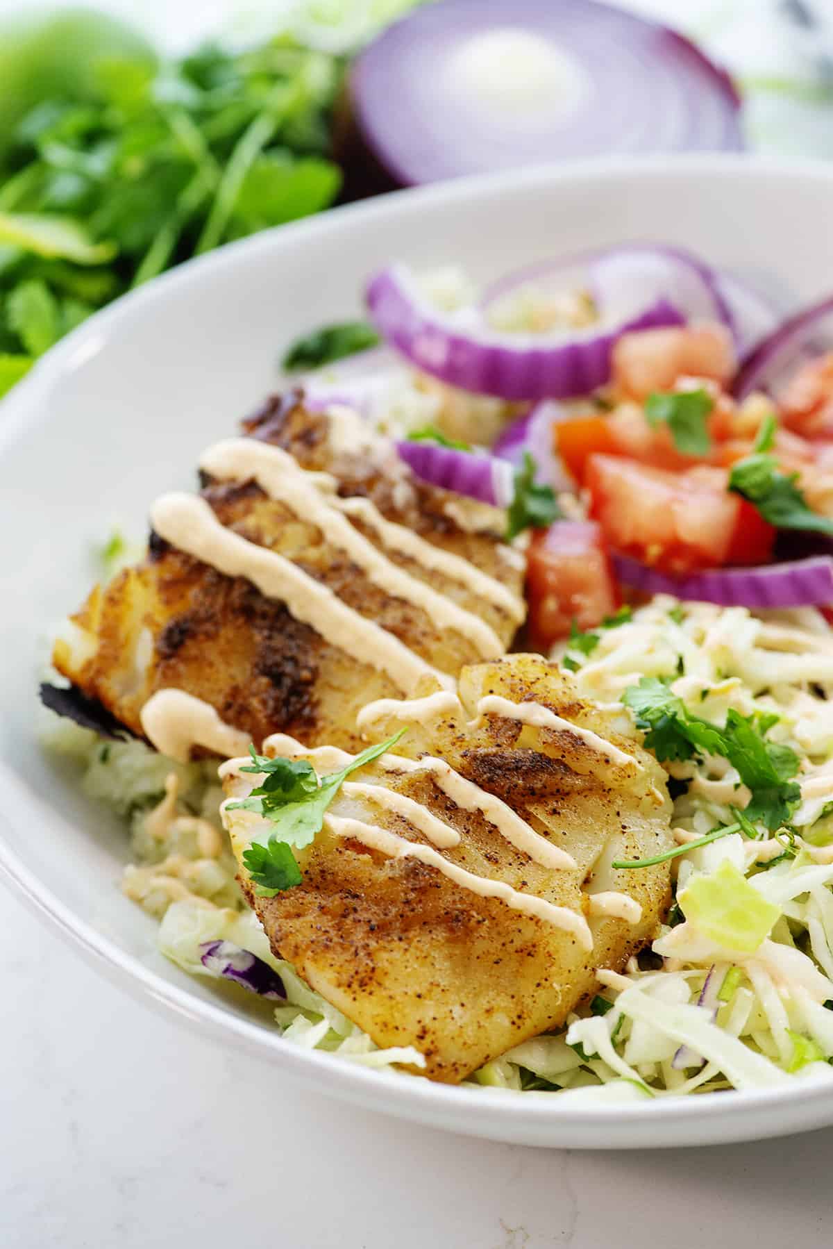 fish taco bowl with sauce drizzled over the top.