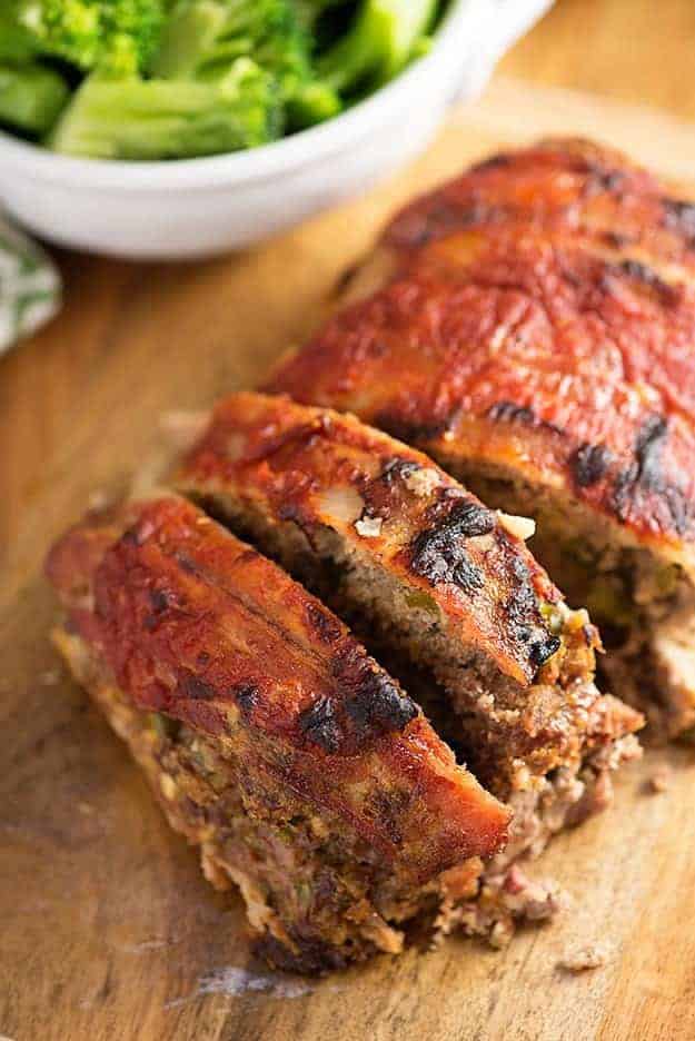 A top down view of sliced, bacon wrapped low carb meatloaf on a wooden cutting board.