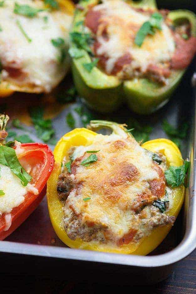A metal baking dish containing four low carb stuffed peppers.