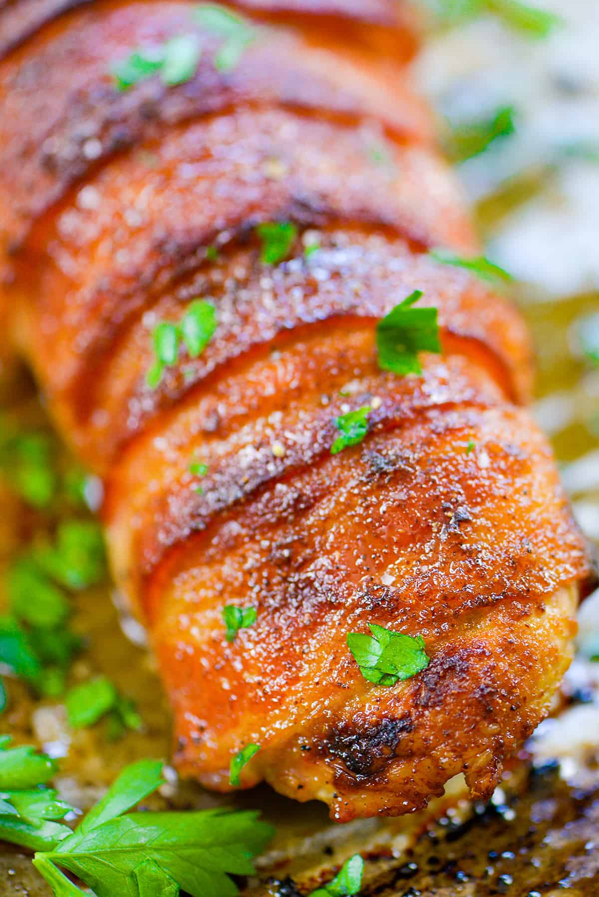 pork tenderloin wrapped in bacon on baking sheet.