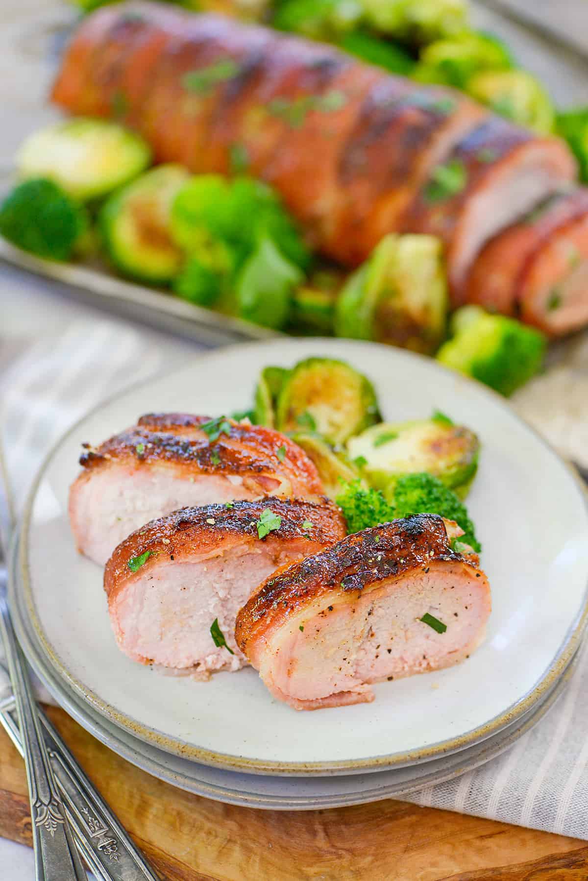 sliced pork tenderloin on plate with broccoli and brussels sprouts.
