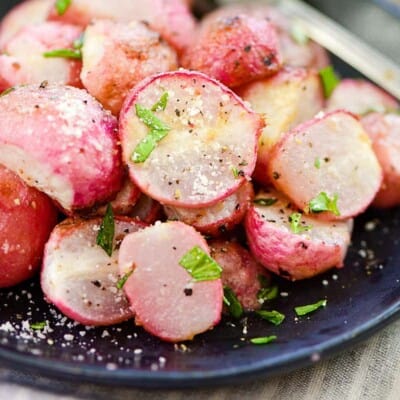 roasted radishes on black plate.