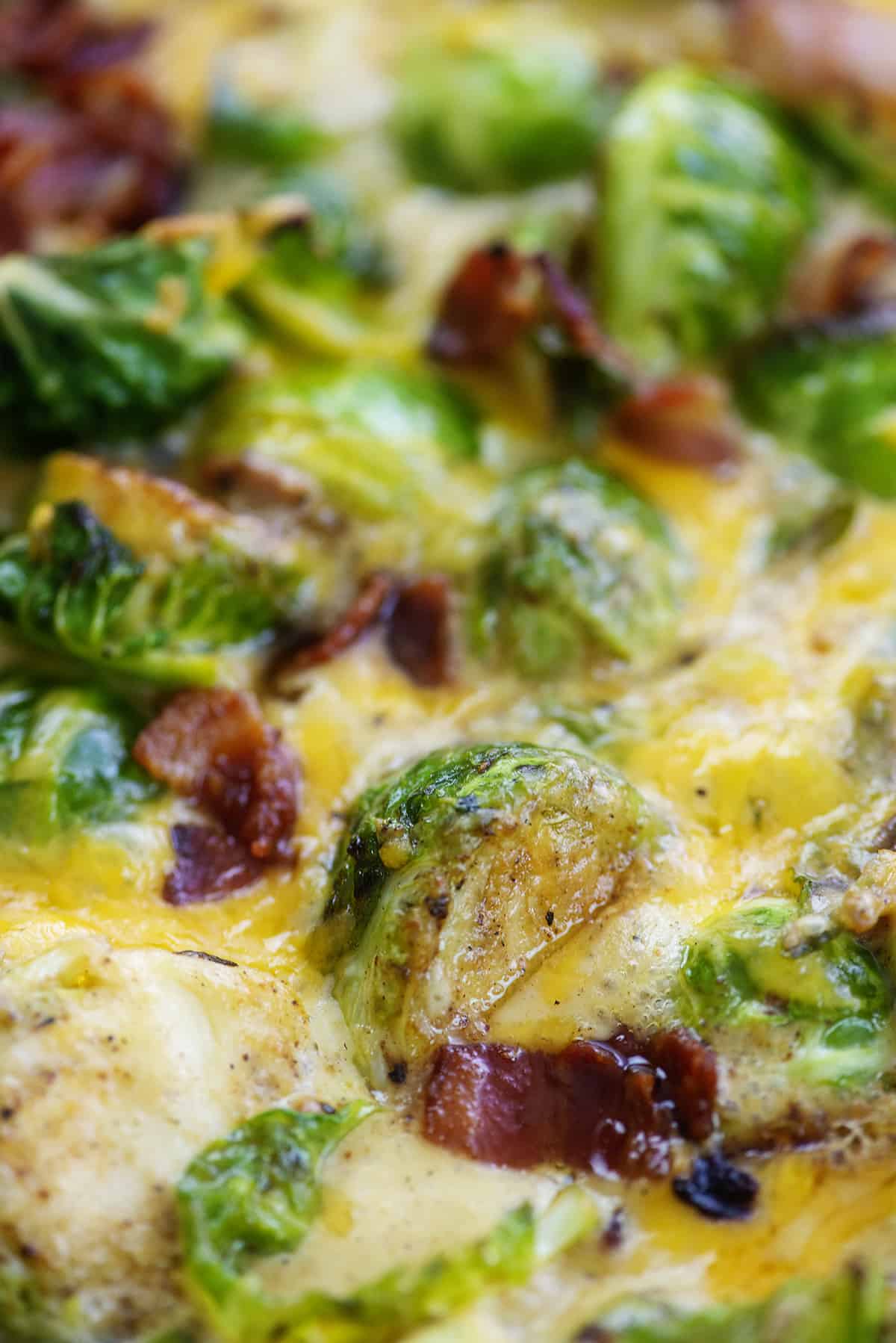 Cheesy Brussels sprouts with bacon in skillet.