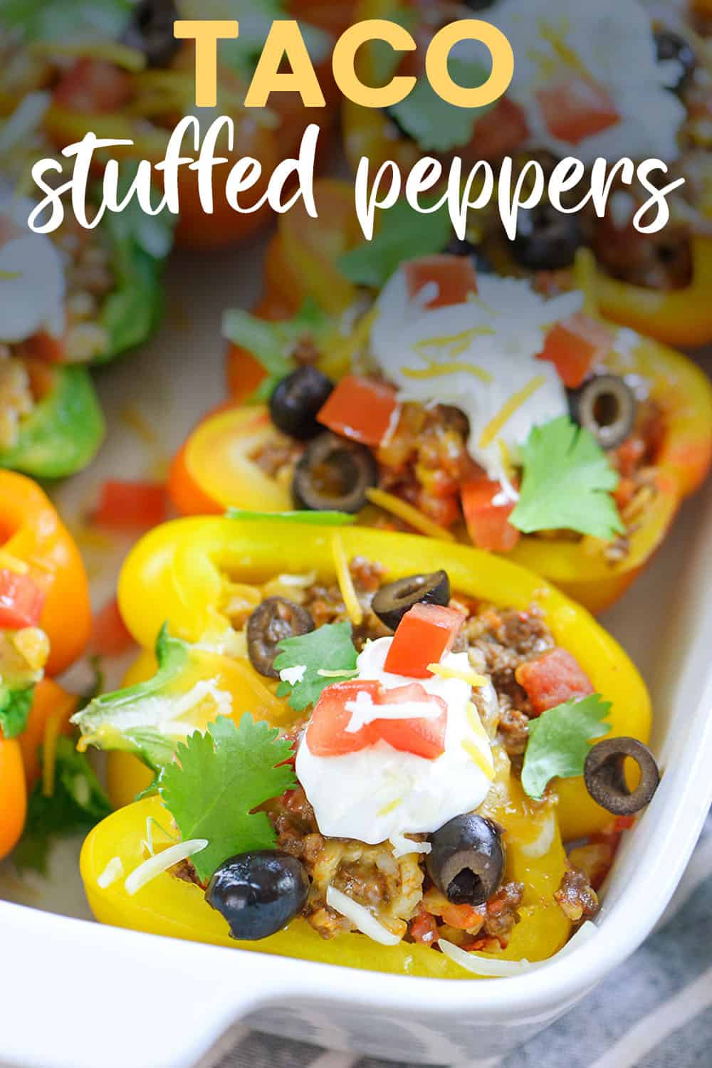 taco stuffed peppers in white baking dish with text for Pinterest.