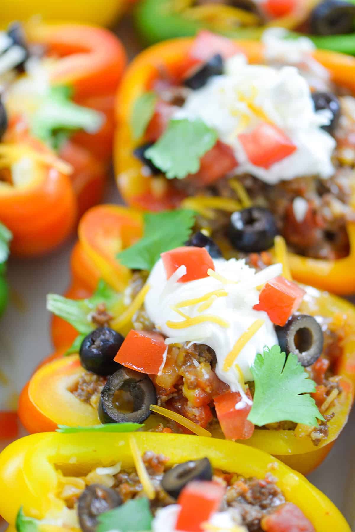 taco stuffed peppers topped with sour cream, black olives, and tomatoes.