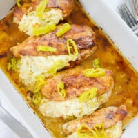 chicken stuffed with cream cheese and peppers in white baking dish.