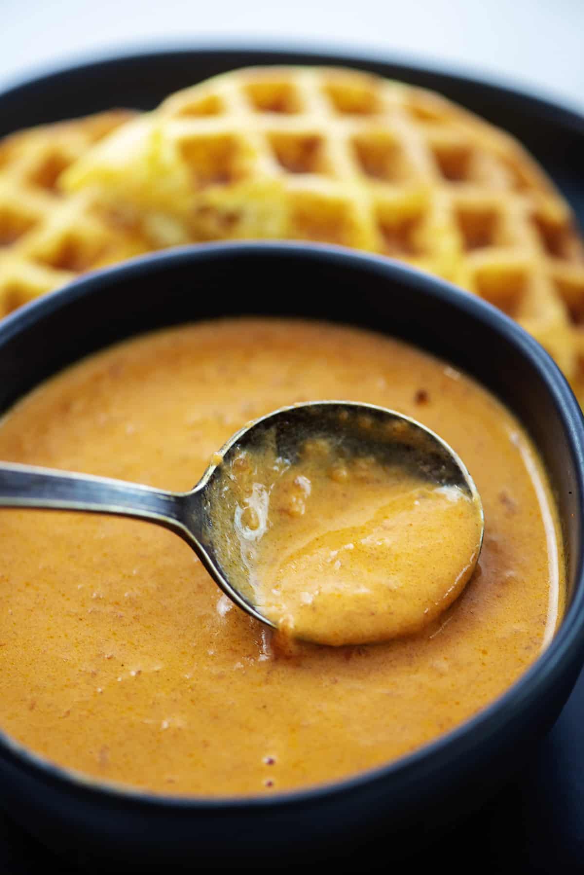 Spoon dipping into bowl of tomato soup.