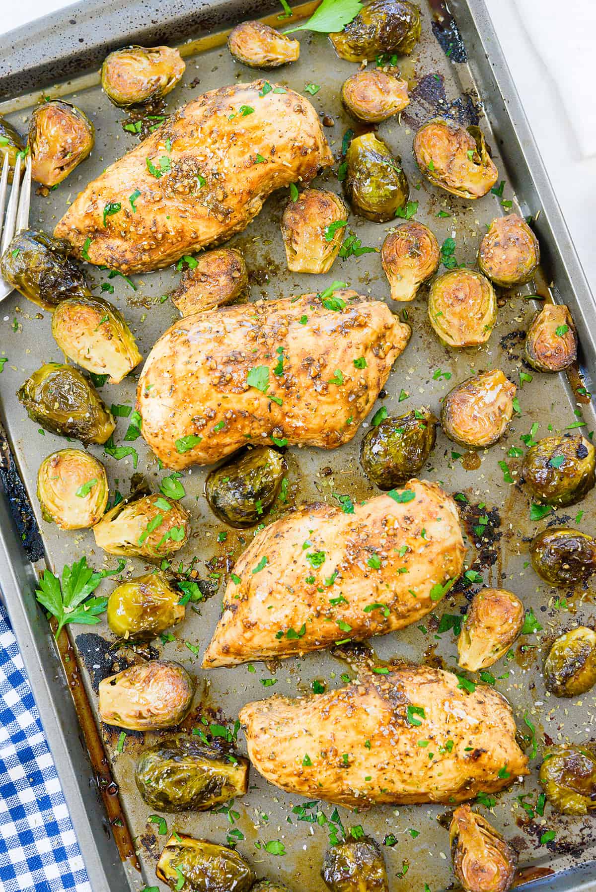 Overhead view of Brussels sprouts and chicken on sheet pan.