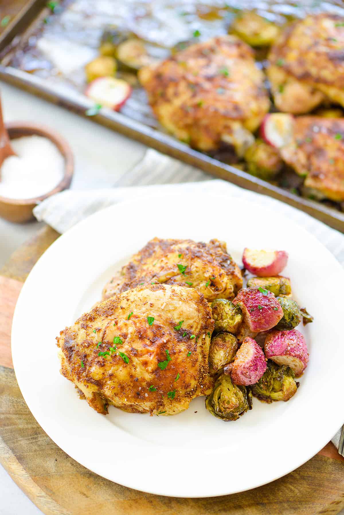 chicken thighs and veggies on small white plate.