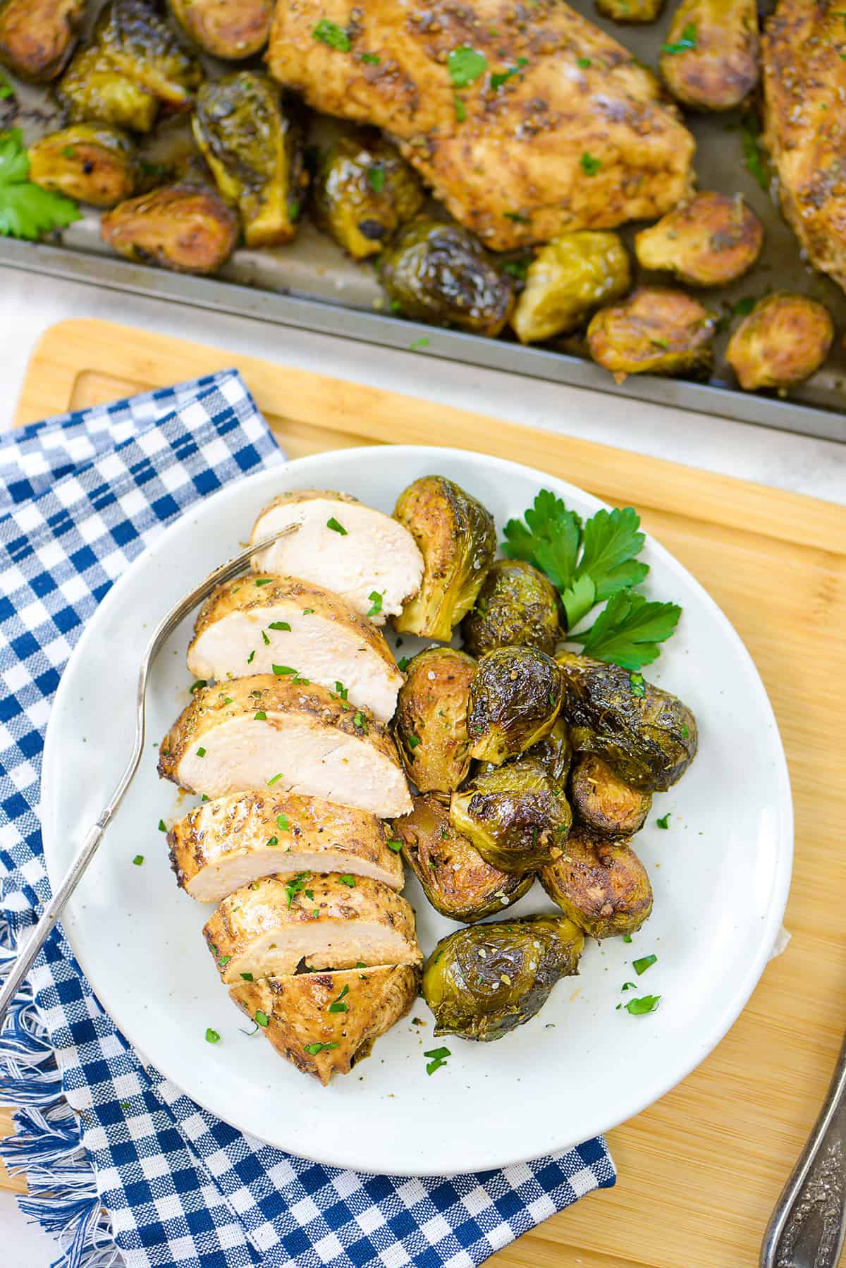 Sliced chicken and roasted Brussels sprouts on white plate.