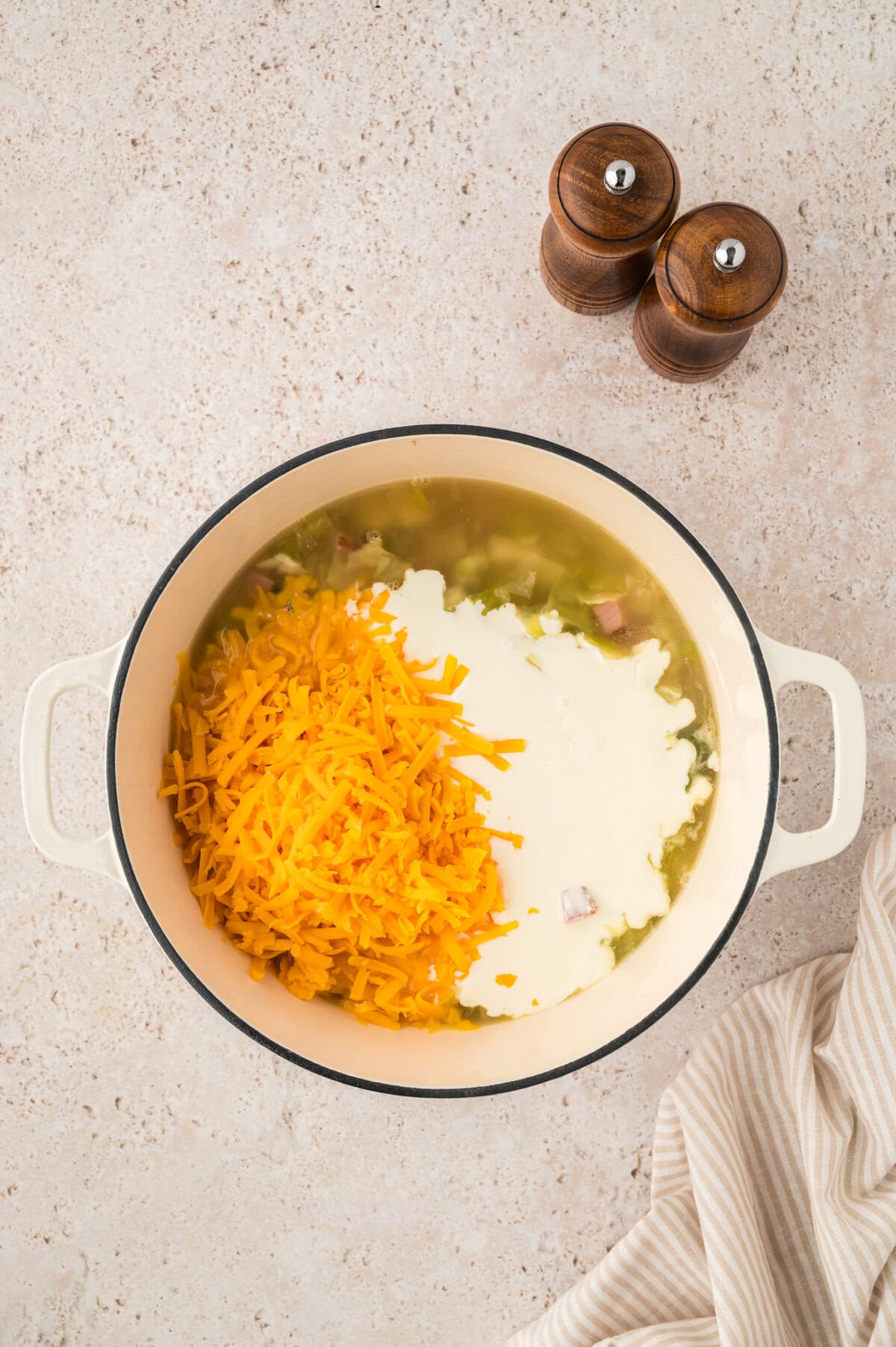 Cream and cheddar in pot of soup.