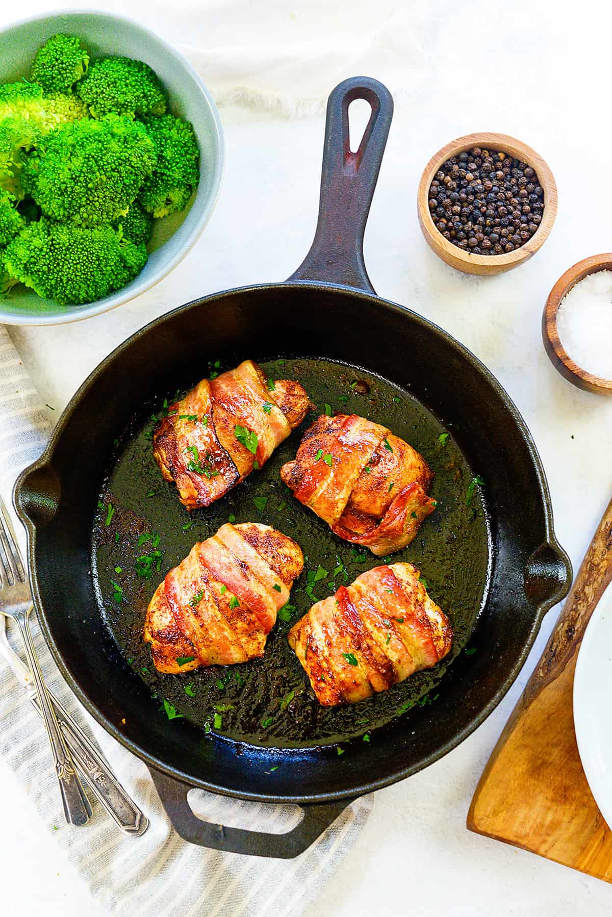 Bacon wrapped chicken thighs in cast iron skillet.