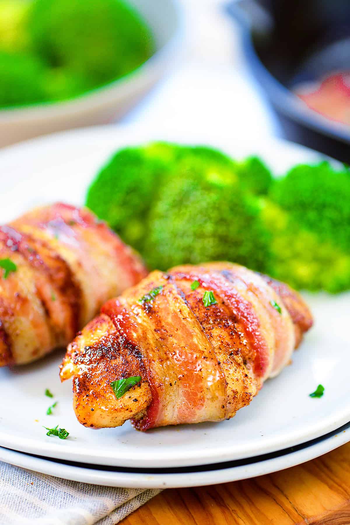 Chicken thighs wrapped in bacon on white plate.