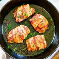Bacon wrapped chicken thighs in cast iron skillet.