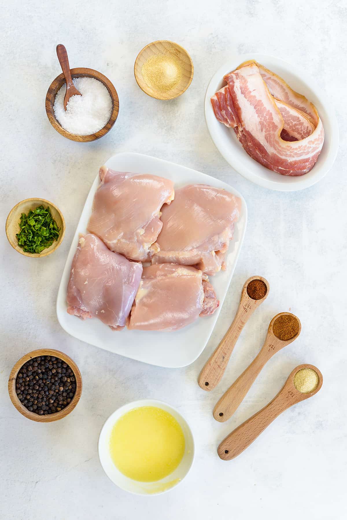 Ingredients for bacon wrapped chicken thighs on countertop.