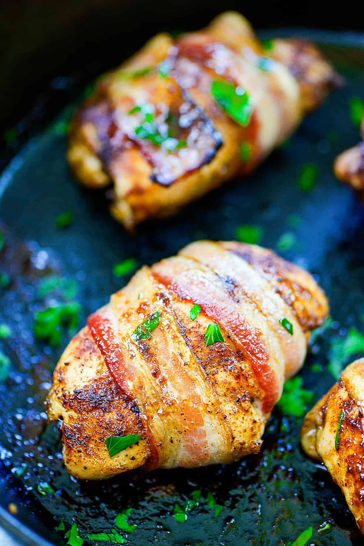 Chicken wrapped in bacon in cast iron skillet.