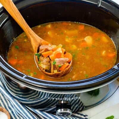 Beef stew in ladle in crockpot.