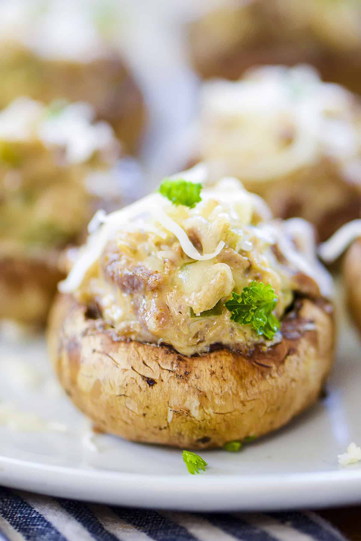 Phily cheese steak stuffed mushroom on white plate.